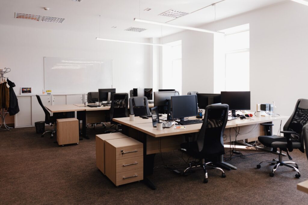 Um escritório com mesas, computadores e cadeiras, representando que o escritório virtual consegue cumprir as mesmas tarefas que um espaço de trabalho físico.