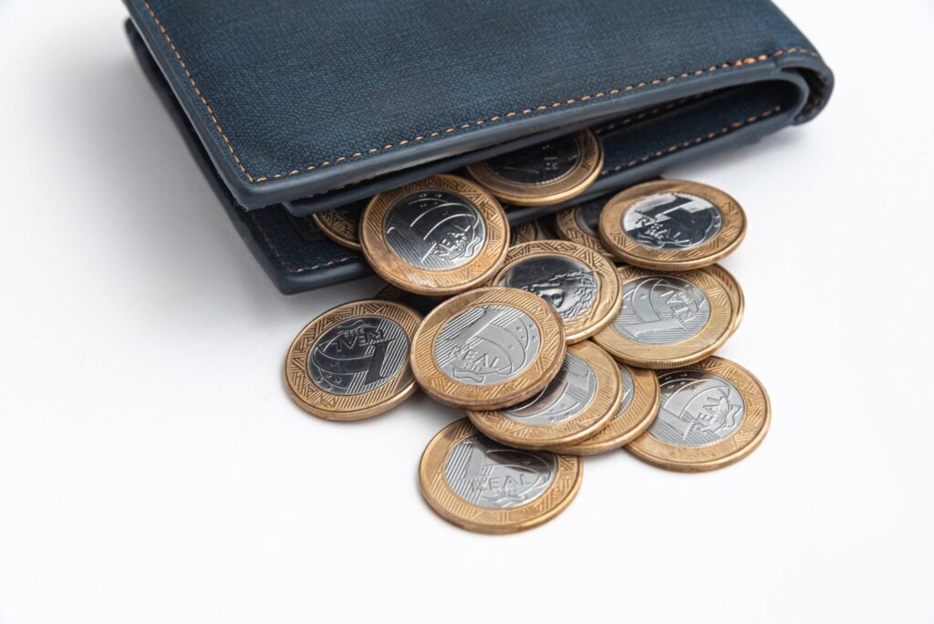 Uma carteira azul-escuro transbordando de moedas de um real.