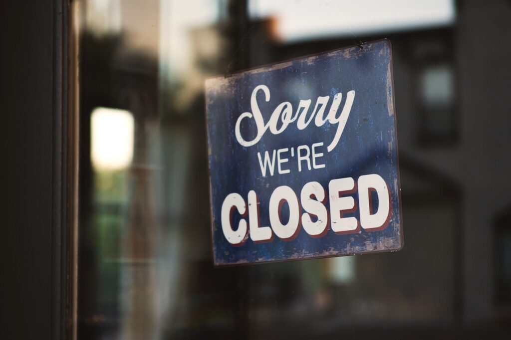 A porta de entrada de um estabelecimento com uma placa onde está escrito “Sorry, we’re closed”, em português, “Desculpe, estamos fechados”.